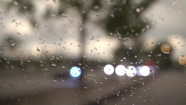 車のフロントガラスで雨の選択的な焦点 道路で車の光の動きのぼけ — ストック動画