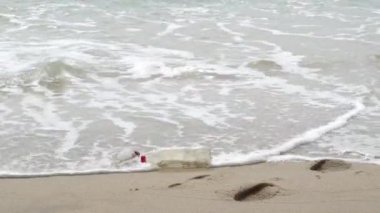 Plajdaki plastik su şişesi dalga dalga sıçrıyor.