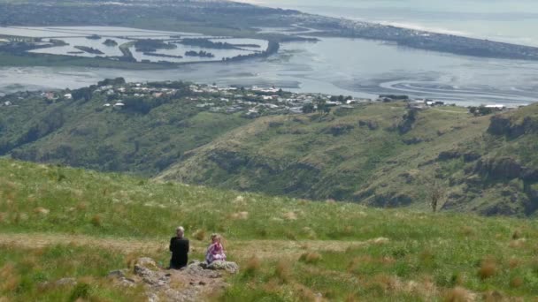 游客们坐在岩石前欣赏港山顶上的景色 — 图库视频影像