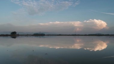 Zaman ayarlı gündoğumu yansıması sel basmış alan üzerinde hareket eden bulut.