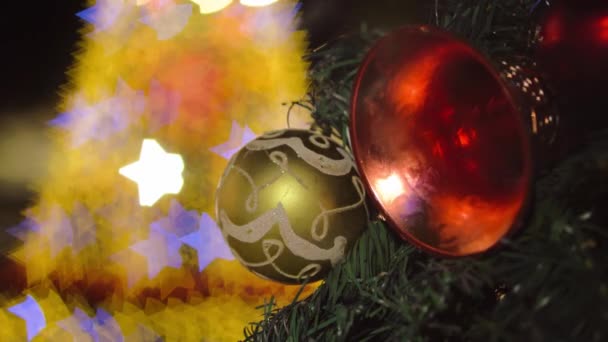 ツリーで選択的なクリスマスボールと鐘の装飾 カラフルな星ボケの背景 — ストック動画