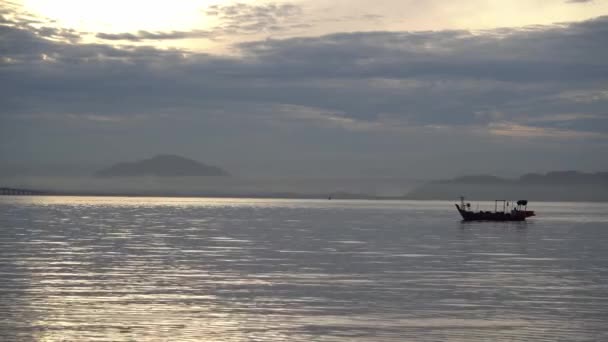 Рыбацкая лодка плывет в море в тумане утреннего рассвета. — стоковое видео