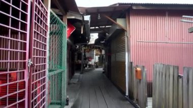 Yerel halk, Chew Jetty 'deki ahşap köprüde motosiklet sürüyor..