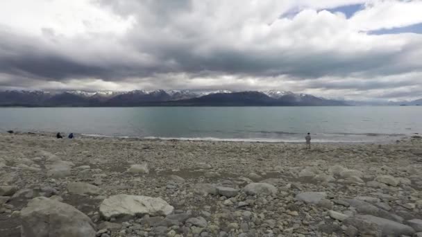 Timelapse turista fotit u jezera Pukaki a rychle se pohybující mrak. — Stock video