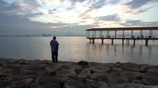 En gammel mann tar vakkert landskap av fiskernes brygge – stockvideo