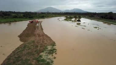 Malezya 'nın kırsal kesiminde yağmur yağdıktan sonra sel basmış nehrin yakınındaki hava manzaralı kazıcı.