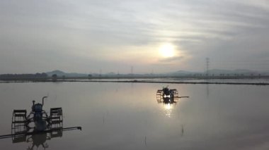 Arka planda güneş alan iki traktöre doğru hareket ediyor..