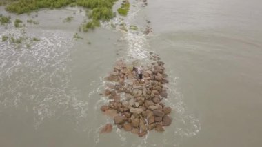 Deniz kıyısında oltayla olta atan bir balıkçı..
