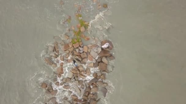 Снимок рыбака с беспилотника в скале, поражённый морской волной. — стоковое видео