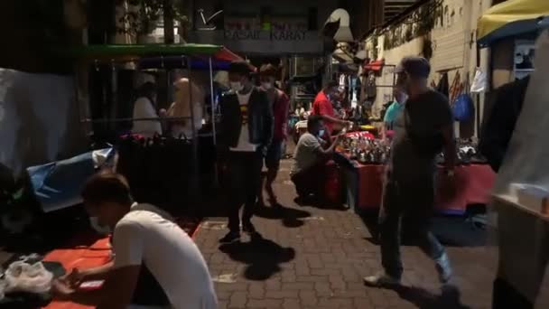 Mensen dragen een masker gaan winkelen op de vlooienmarkt — Stockvideo