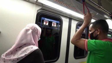 İnsanlar LRT treninde maske takıyor.