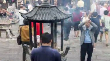 Zaman ayarlı bir manzara. Seyirciler joss çubuğu yakıyor. Tapınakta dua ediyorlar.