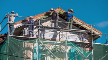 İnsanlar mavi gökyüzündeki eski miras binalarını restore ediyorlar.