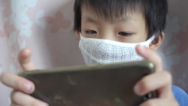 Klein Kind Dragen Negatieve Ion Gezichtsmasker Spelen Mobiele Telefoon — Stockvideo