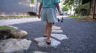 Bir kızın bacağına odaklan ve Japon bahçesindeki taşın üzerinde koş..