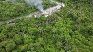 Açık hava manzaralı yeşil yemyeşil çimenlikte çöpler yanıyor.