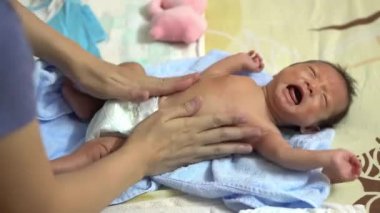 Anne yeni doğmuş bebeğe yatakta losyon sür. Aile, aşk konsepti