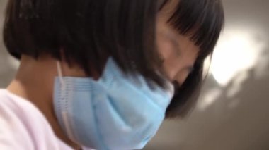 Çinli çocuğun yüzünü kapat ve yüz maskesi tak. Ödevine bak. COVID-19 pandemik yeni normal