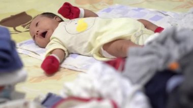 Yeni doğmuş bebeğe odaklan. Odada uzan. Ön plan giysileri açmak.