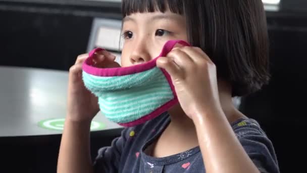女の子の子供は ファブリックフェイスマスクを着用 コロナウイルス発生時の新しい正常パンデミック — ストック動画