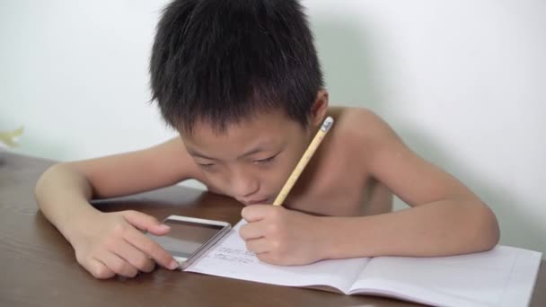 一个中国孩子在用手机进行电子学习时正在做作业 — 图库视频影像