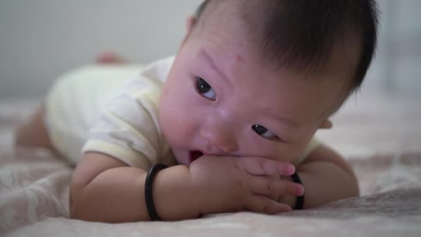 アジアの赤ちゃん遊びます唾液とともに手オンベッド — ストック動画