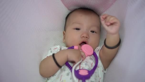 赤ちゃんレイダウンでクレイドルとともにピンクの聴診器おもちゃ — ストック動画