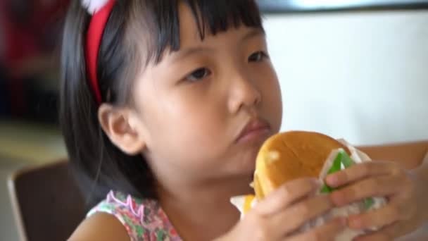 中国の女の子とともにクリスマス鹿毛バンド食べるハンバーガーにレストラン — ストック動画