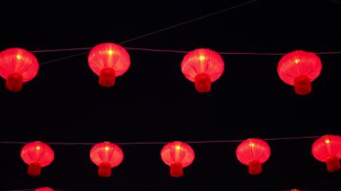 Kablodan sarkan kırmızı fenerler. Fenerler yanıyor. Görüntüde bir sürü fener var.