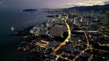 Arka planda büyük bir su kütlesi olan bir şehir. Drone görüntüsü Jelutong, Penang geceleri