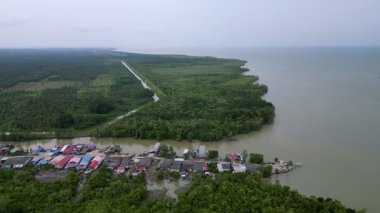 Bir nehir bir petrol palmiyesinin içinden akar ve diğer tarafta küçük bir köy vardır. Su kahverengi ve bulanık. Aerial Sungai Ayam, Batu Pahat