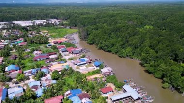 Evleri ve nehri olan bir kasaba. Evler kırmızı ve mavi. Nehir kahverengi. Hava Kuala Sepetang balıkçı köyü