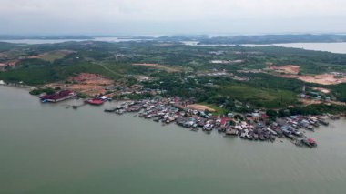 Arka planda su birikintisi olan bir kasaba manzarası. Su yeşil ve kasaba evlerle dolu. Kepri Deniz Ürünleri Restoranı yakınlarındaki hava manzaralı Riau