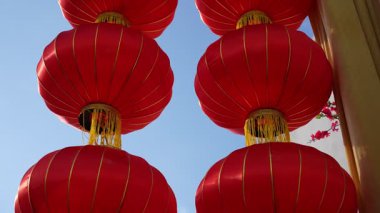 Dört kırmızı fener bir binadan sarkıyor. Gökyüzü mavi