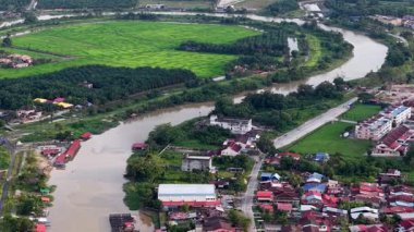 Nehir, her iki tarafında evler ve binalar olan bir kasabadan geçiyor. Havadan Bandar Baharu, Kedah