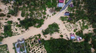 Yol ve evlerle dolu sel basmış bir bölge. Yolda bir araba var. Evler uzak mesafede. Junjung, Kedah, hava manzaralı sel baskını