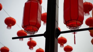 Metal bir direğe asılı iki kırmızı fener var. Direkten sarkan bir sürü kırmızı fener var.