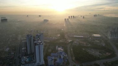 Önünde büyük bir bina ve arkasında büyük bir bina olan bir şehir. Gökyüzü puslu ve güneş batıyor.