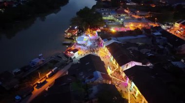 Nibong Tebal, Penang, Malezya - 19 Ocak 2025: Hava gece görüşü, kültürel canlılık ve şenlikli atmosferi harmanlayarak sokağın karşısına dizilmiş kırmızı fener süslemelerini ön plana çıkarıyor.