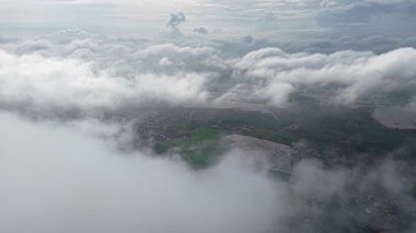 Sisli bir günde Bukit Mertajam tarım arazisi ve köyü üzerindeki sis ve alçak bulutları gösteren tepeden aşağıya bakan drone görüntüleri.