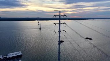 Gün batımında Johor Nehri 'nde sakin bir nehrin büyüleyici görüntüsü. Titreyen bir gökyüzüne karşı elektrik hatları var.,