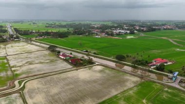 İnsansız hava aracı görüntüleri pirinç tarlaları, sulama kanalları, sel baskınları ve yukarıdaki kırsal evleri gösteriyor..