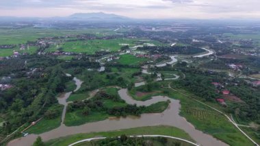 İnsansız hava aracı Labuh Banting Nehri 'nin akıntıları, pirinç tarlaları, köyler ve çevreleyen ova manzarası üzerinde görünüyor..