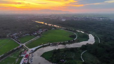 Gökyüzünden görünen Labuh Banting nehri gün batımında pirinç tarlaları, köy rıhtımları ve dolambaçlı yollar ile kıvrılır..