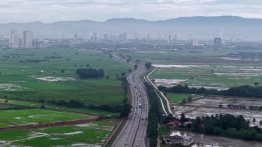 Penanti çeltik tarlalarının hava aracı görüntüsü. Otoyolu ve uzak şehir silueti var..