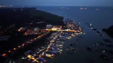 Geceleri kıyı şeridi yakınlarında parlayan Kukup yerleşim evlerinin havadan görünüşü.