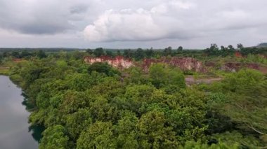 Perai köyü üzerindeki gökyüzü insansız hava aracı görüntüsü yoğun ormanı, kızıl kayalıkları ve bitişik su kaynağını gösteriyor..