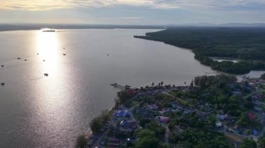 Drone perspektifi dağınık evler, tropikal yeşillikler ve tarım arazisi üzerinde parlayan ufuk ile kırsal Johor Lama 'yı yakalıyor.