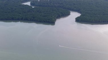 erial çekimi, Mangrove ormanının arka planında Johor Nehri 'nde süzülen tekneyi vurguluyor
