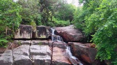 İnsansız hava aracı görüntüsü Batu Ferringhi Şelalesi 'nin yoğun tropikal ormanlarda parıldayan havuzlarla birlikte aktığını vurguluyor.